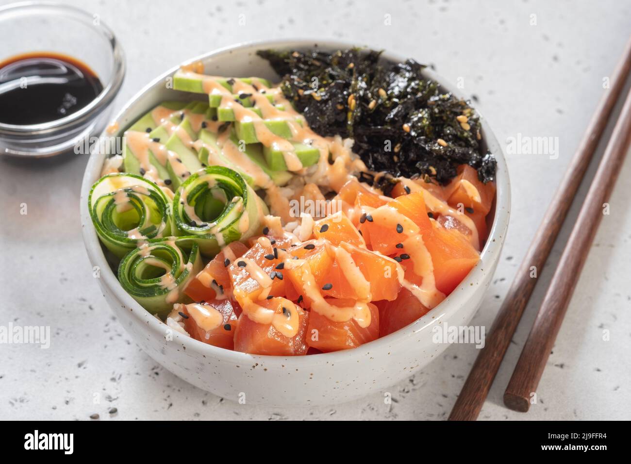Hawaiian Salmon Poke Bowl with avocado, cucumber , rice and sesame seeds. Sushi bowl. Organic and healthy food. Stock Photo