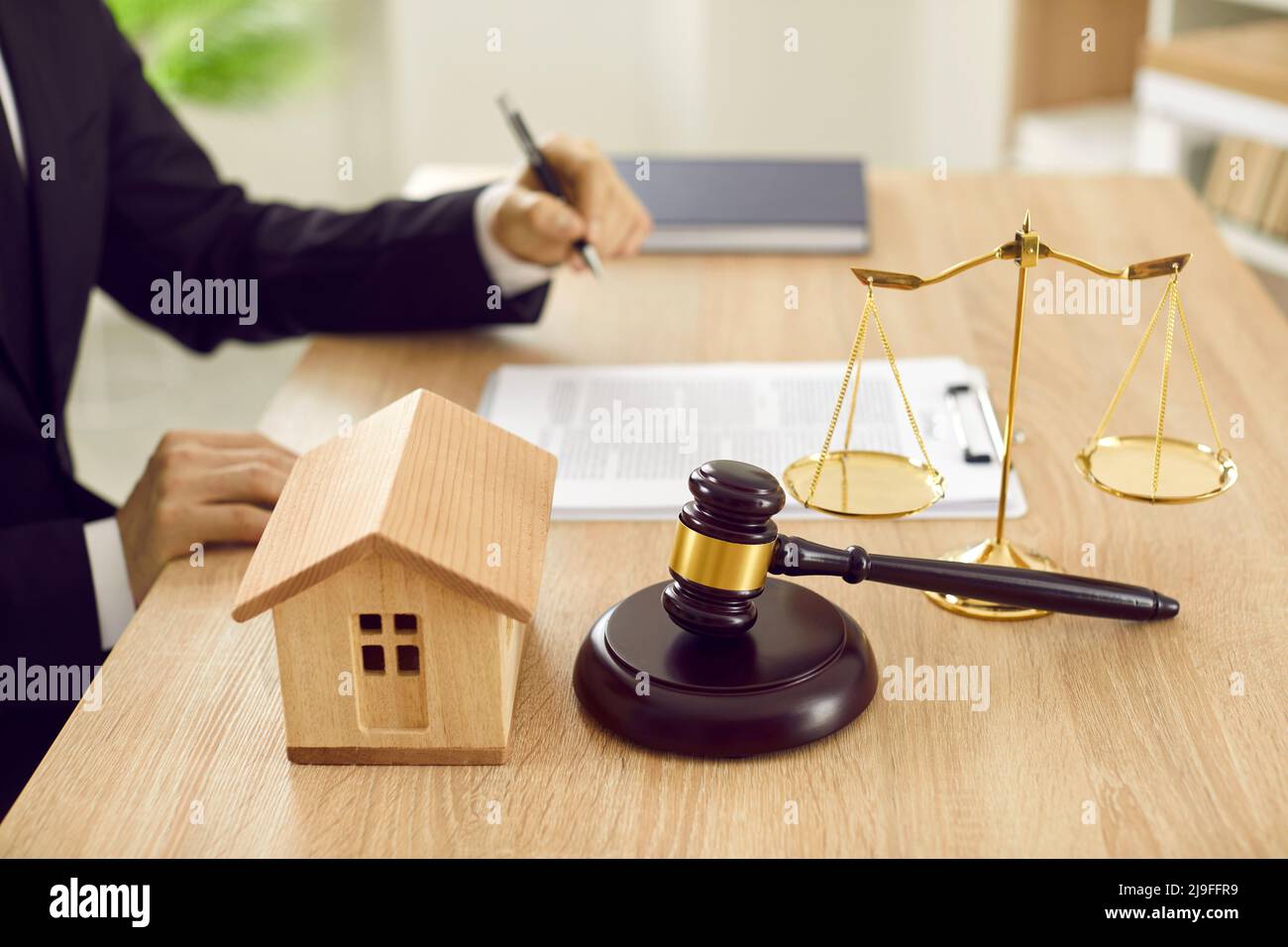 Real estate lawyer working at his desk with toy house, gavel, and scales of justice Stock Photo