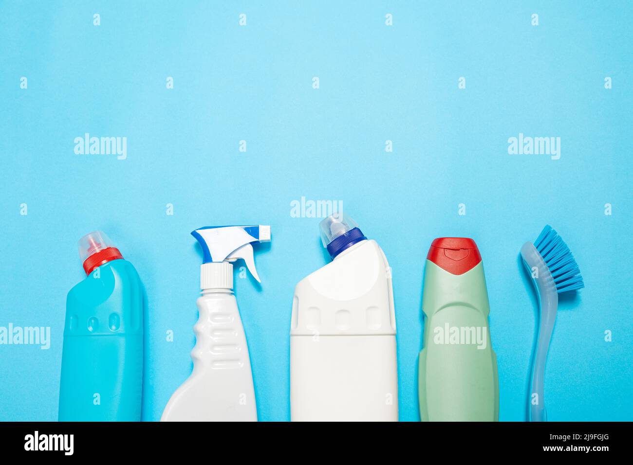 House cleaning supplies on blue background. Row of plastic bottles with
