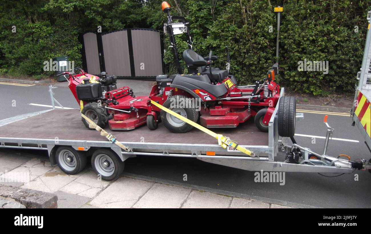 industrial petrol lawn mowers on the back of a trailer on the road. Lancashire, UK Stock Photo