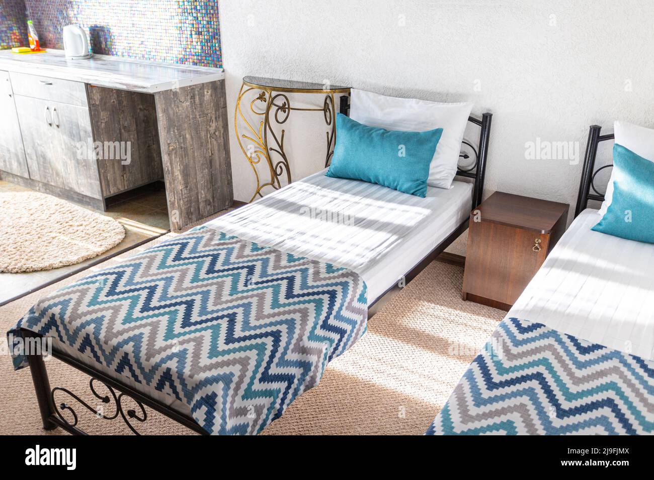 Two beds in a hotel room. white and blue pillows on a white sheet sunbeams Stock Photo