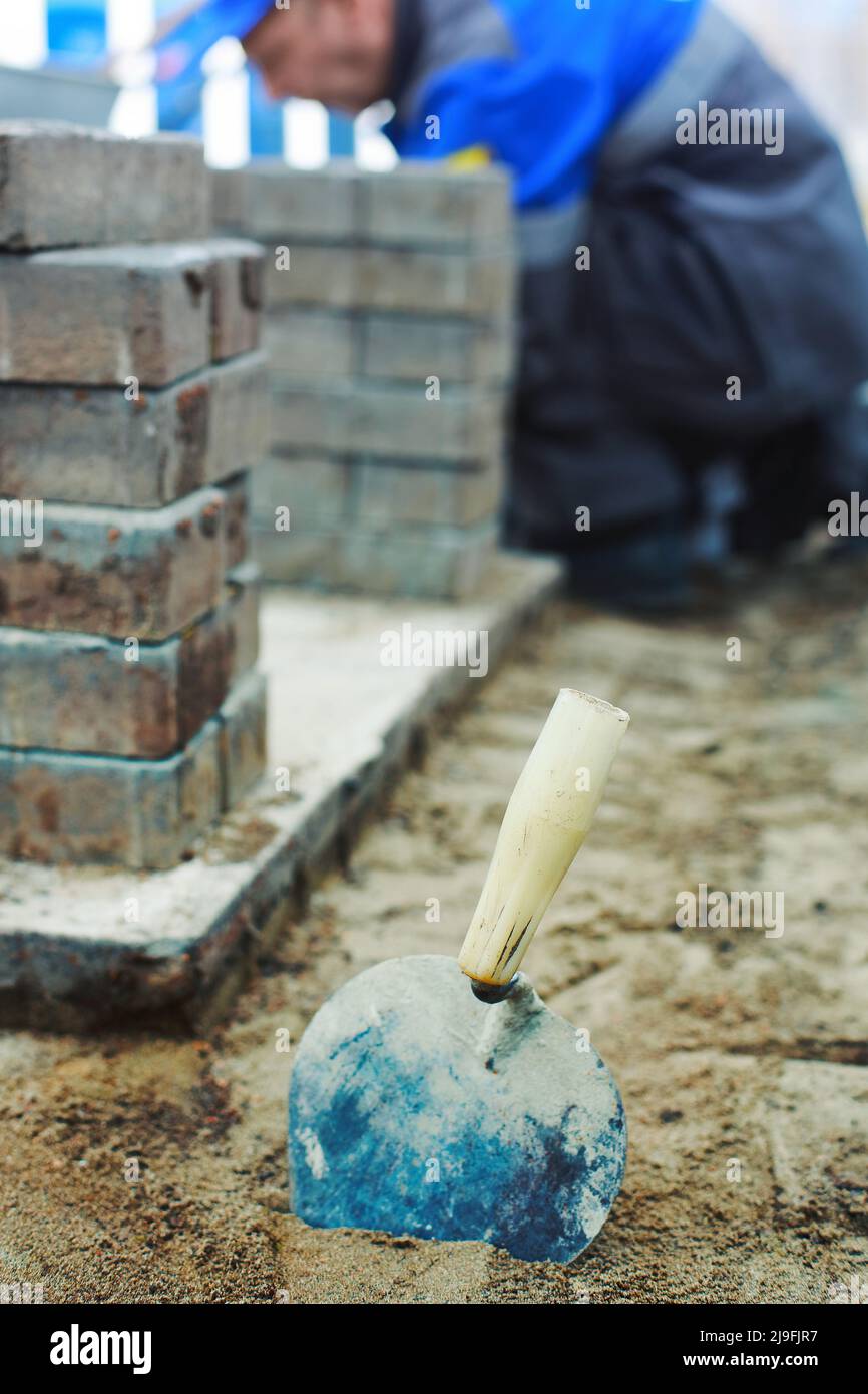 Bricklayer's construction trowel is stuck in sand. Background. Stock Photo