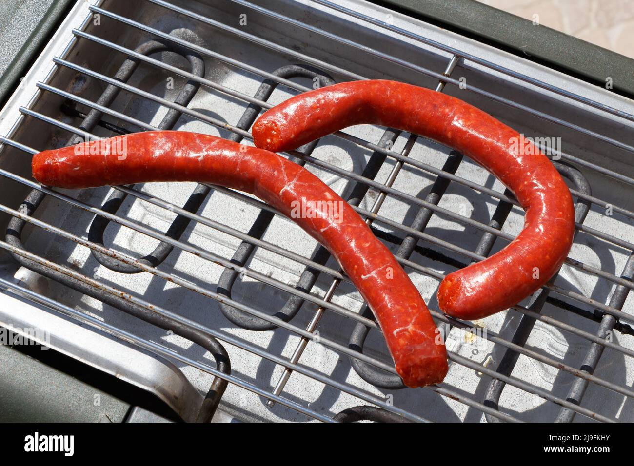 Two raw merguez on electric barbecue Stock Photo