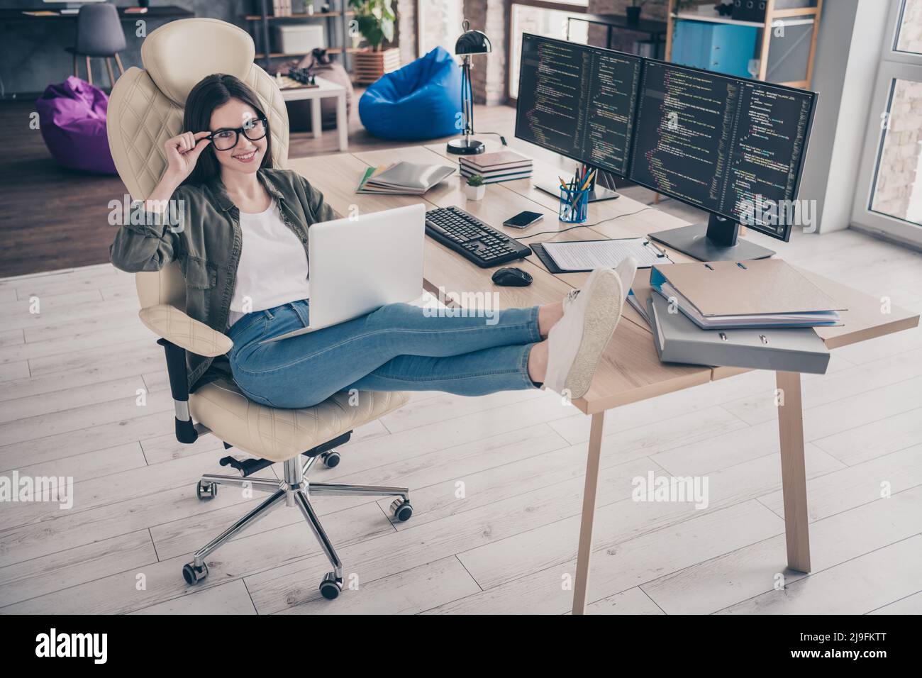Full length photo of young cheerful girl sit stool open space use laptop designer tester workstation eyewear indoors Stock Photo