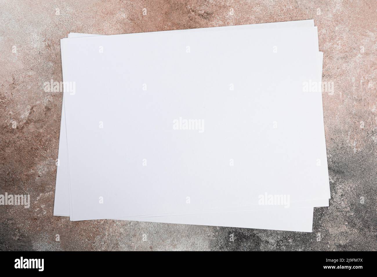 several sheets of paper in a pile of a4 a5 business card on a grunge table. Stock Photo