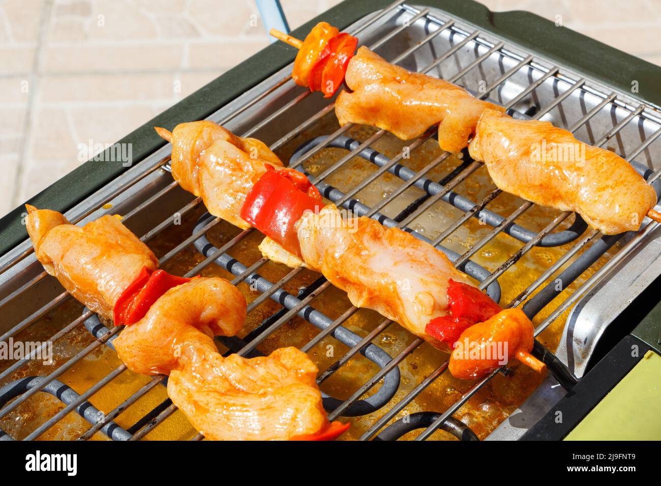 Marinated chicken brochette on the rack of an electric barbecue Stock Photo