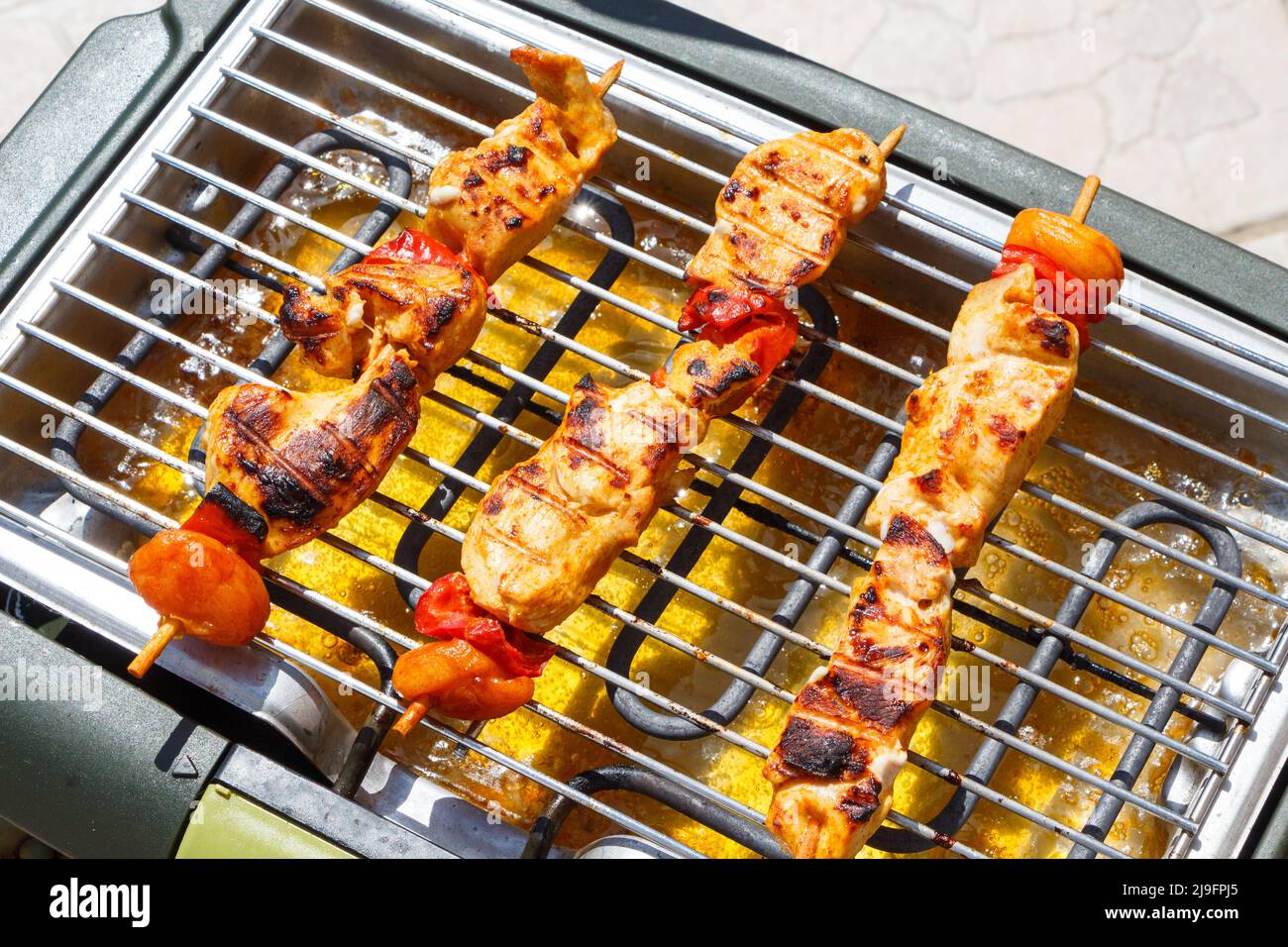 Marinated chicken brochette on electric barbecue Stock Photo