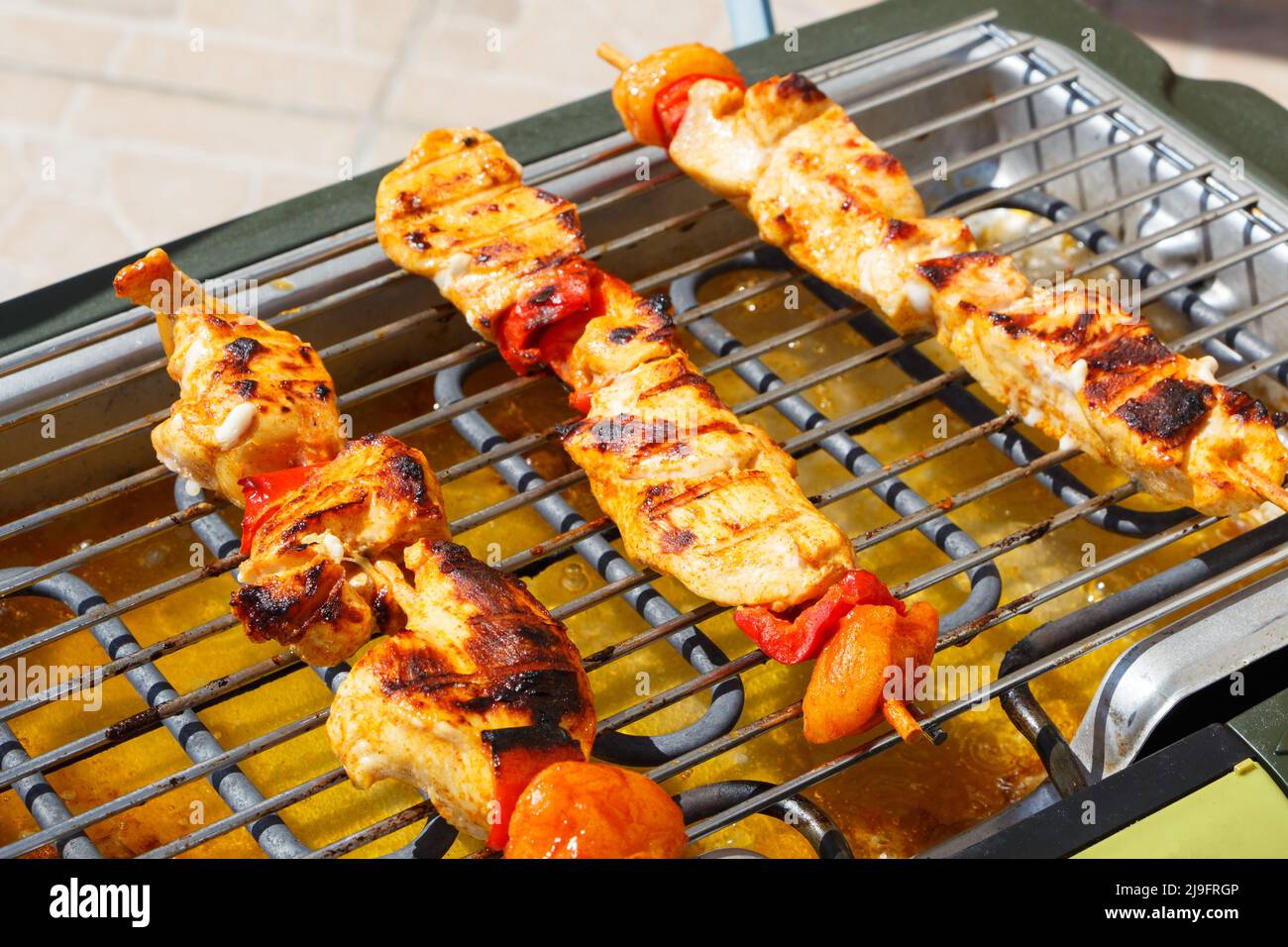 Marinated chicken brochette on the grid of an electric barbecue Stock Photo