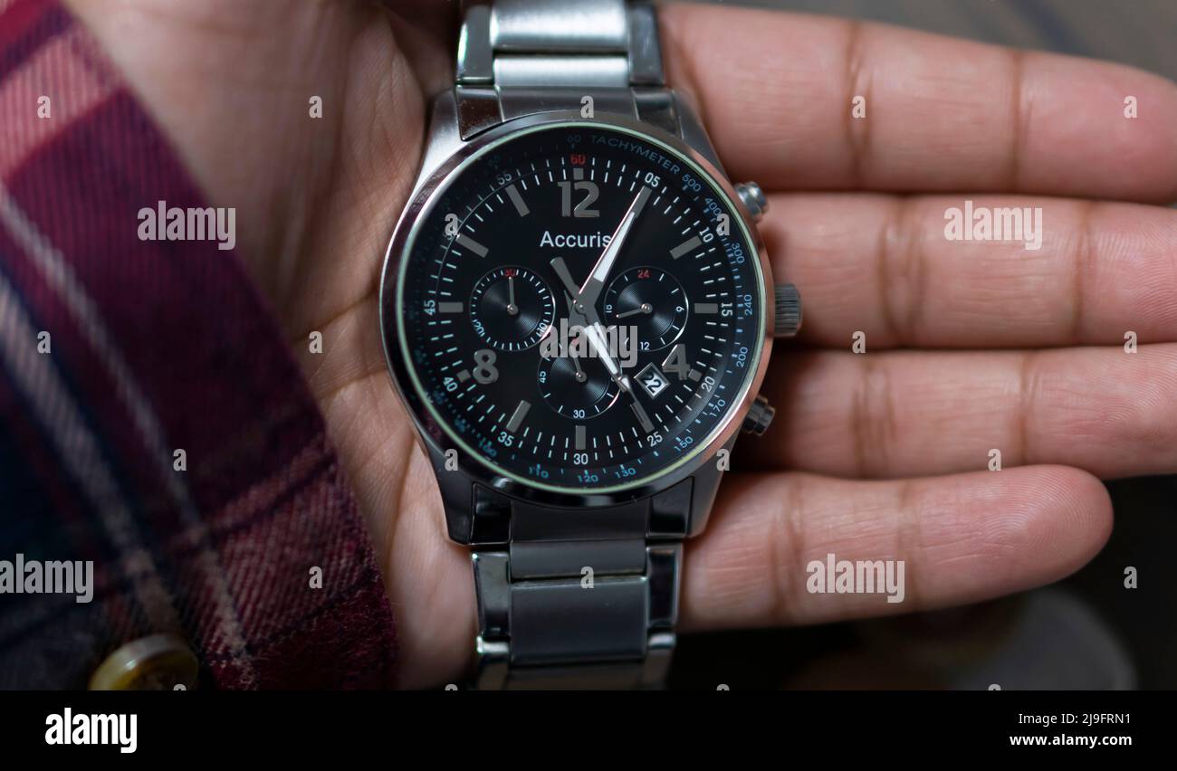 Man holding a silver analogue watch Stock Photo