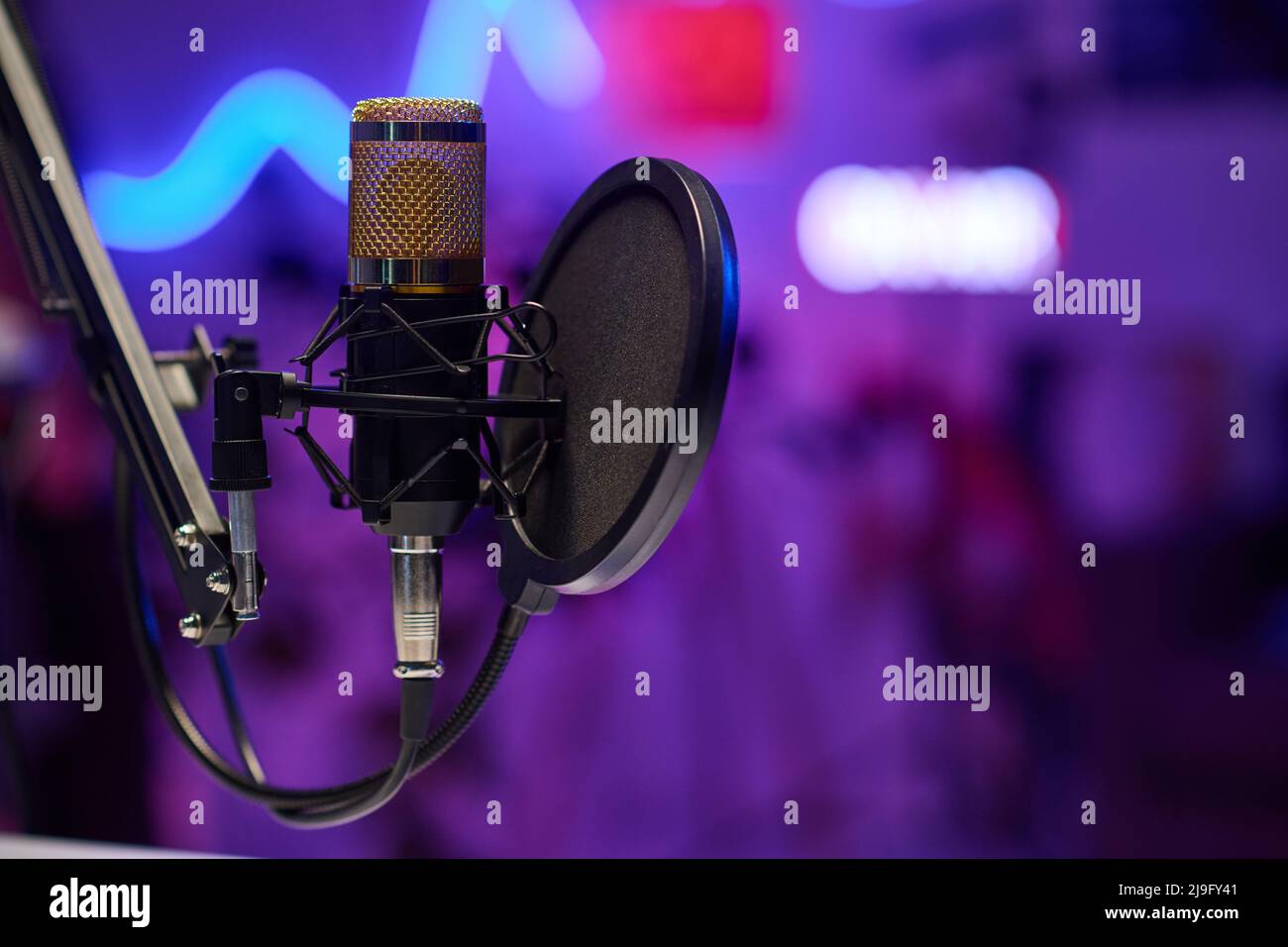 Horizontal no people selective focus shot of microphone with disc pop filter in modern recording studio Stock Photo