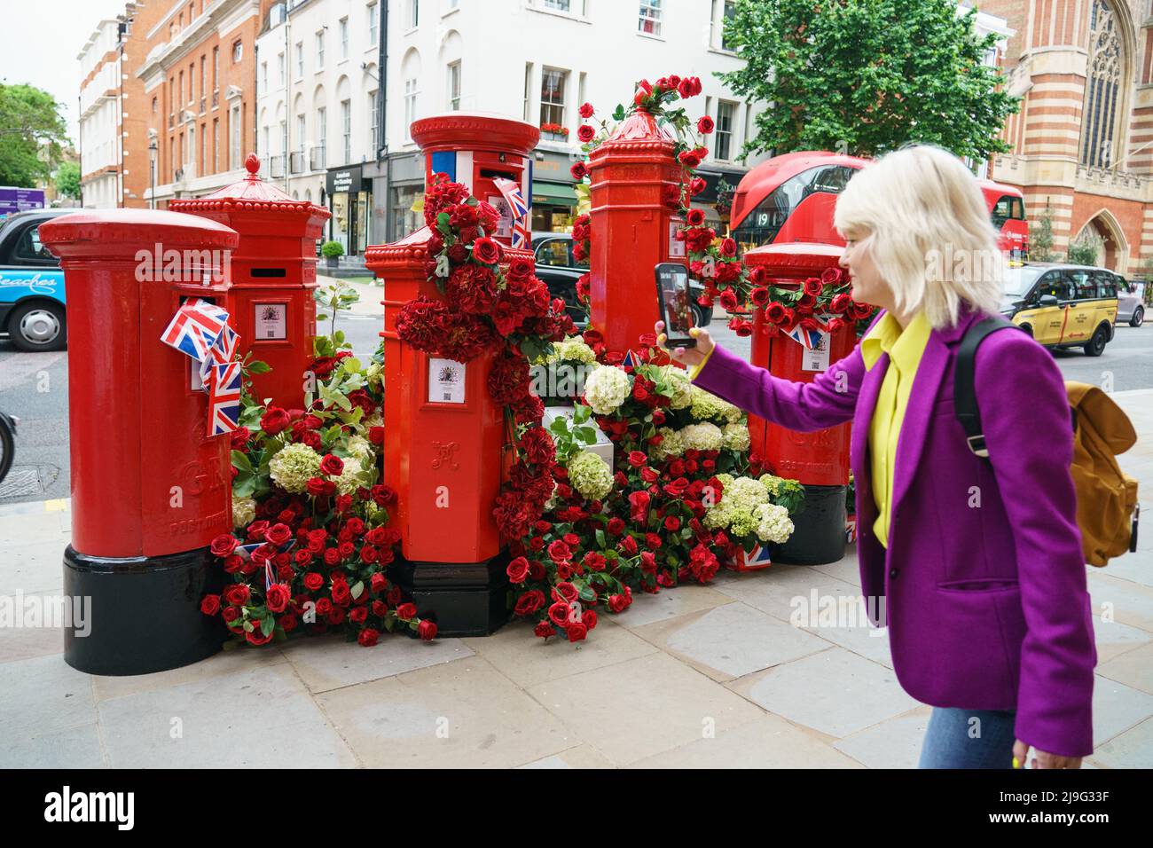 A woman takes a photo of a floral postbox display in Chelsea, west ...