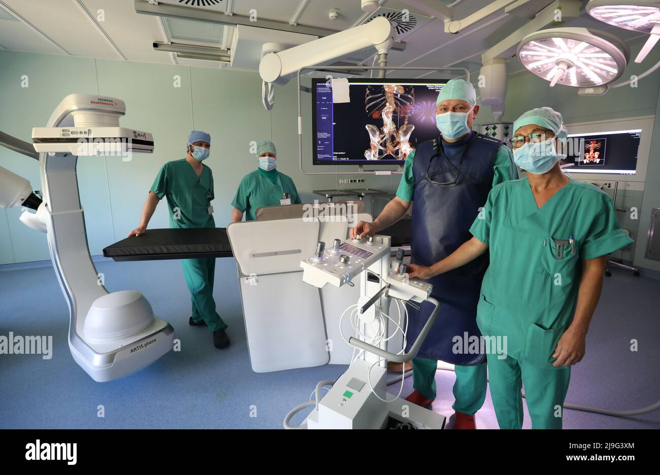 rostock-germany-23rd-may-2022-torsten-kleber-l-r-senior-physician-jeannette-k-nig-nurse-bernd-kortmann-senior-physician-and-nicole-krokowski-nurse-stand-in-the-hybrid-or-with-a-latest-generation-large-scale-radiological-device