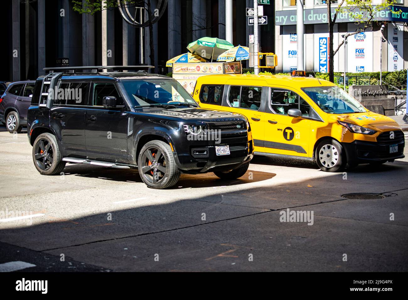 New Land Rover Defender in New York neben einem Yellow Cab Taxi Stock Photo