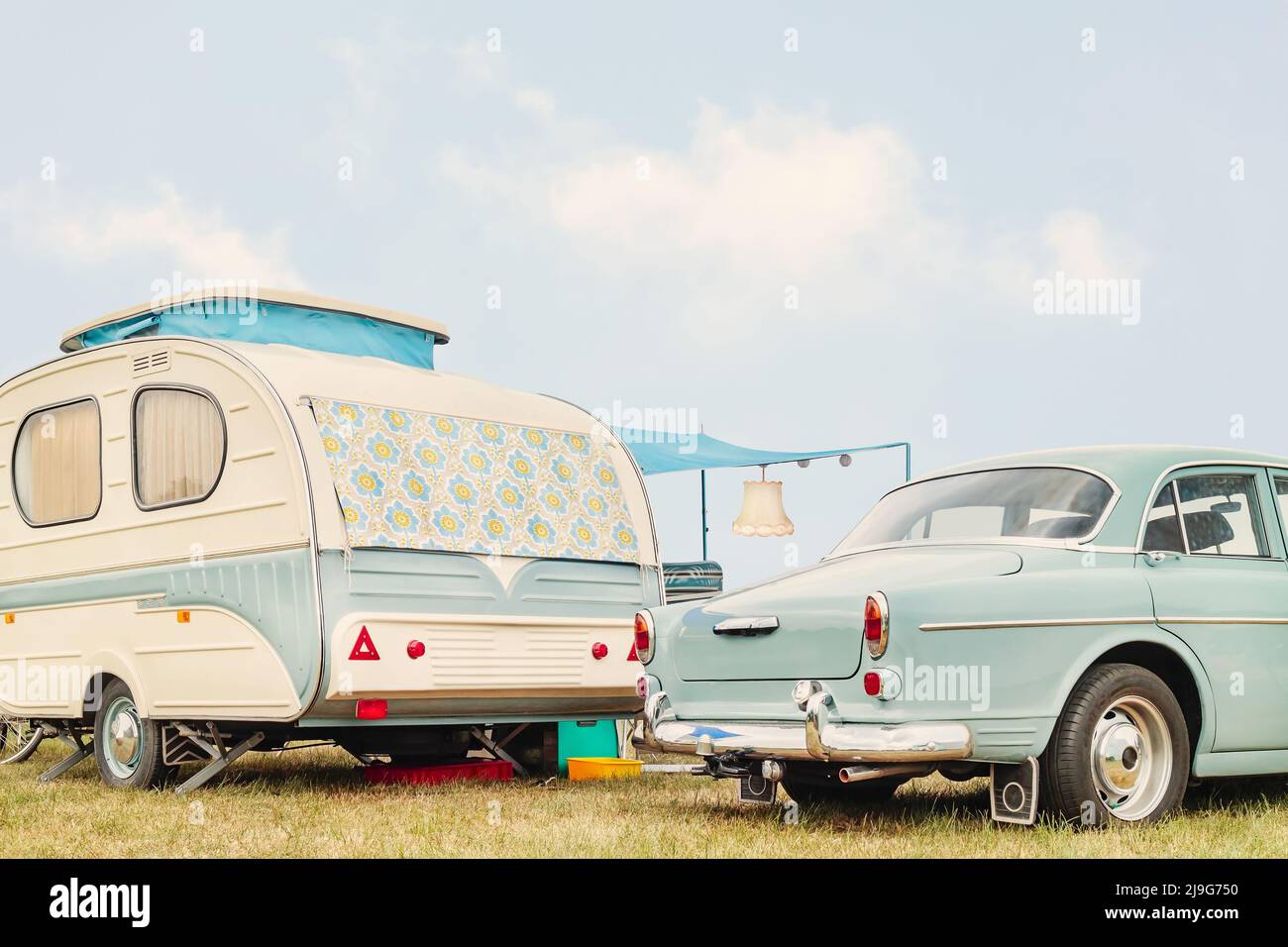 Retro classic car and seventies caravan with flower curtains in two-tone white with green Stock Photo
