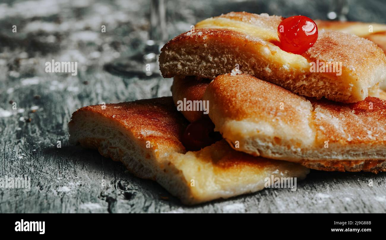 closeup of some pieces of coca de sant joan, a typical sweet flat cake from catalonia, spain, eaten on saint johns eve, on a gray rustic wooden table, Stock Photo