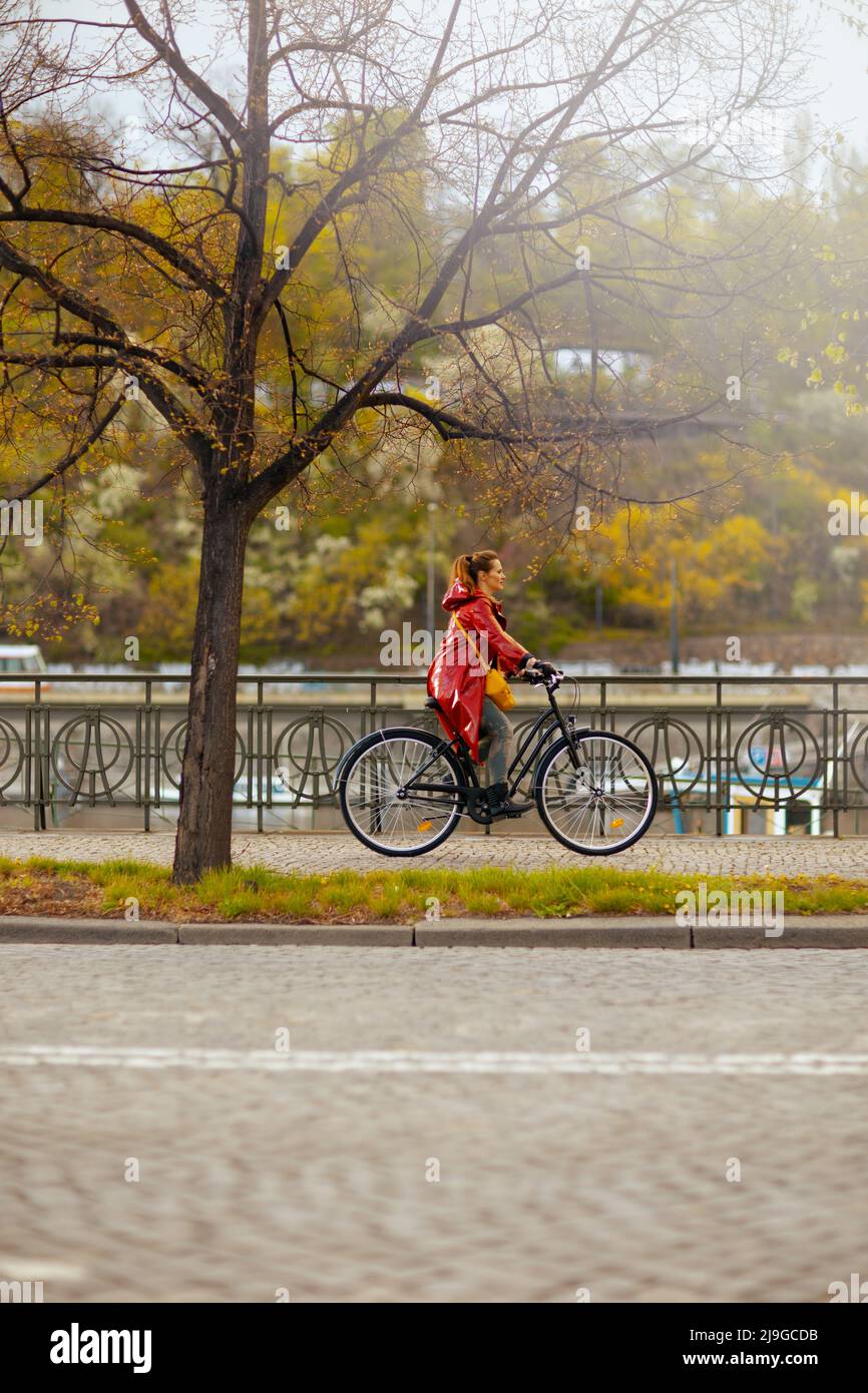 modern woman in red rain coat outdoors in the city riding bicycle Stock ...