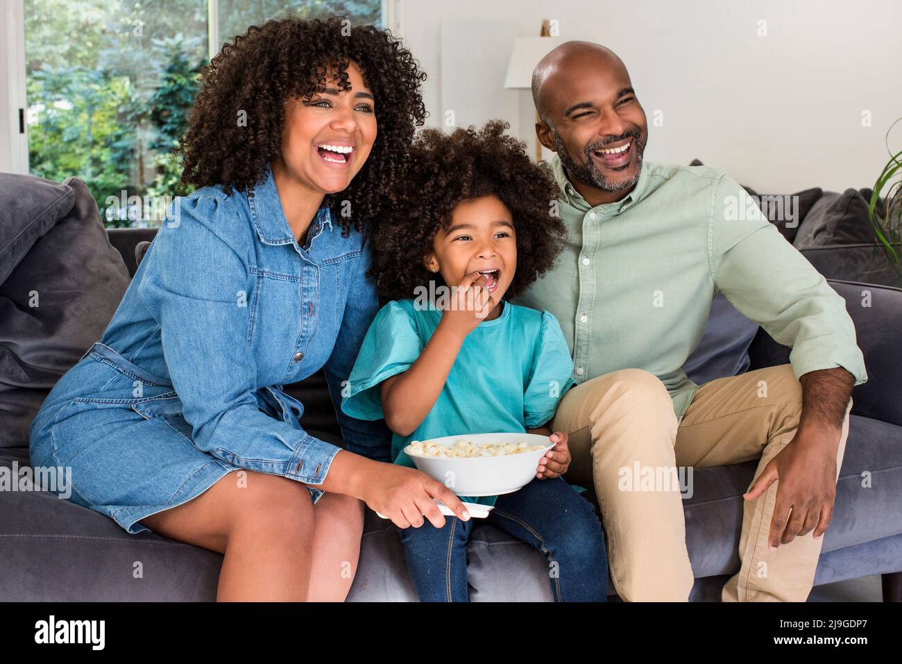 Happy family watching television together while sitting on sofa Stock ...