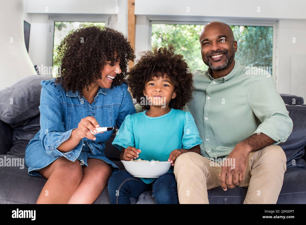 Happy family watching television together while sitting on sofa Stock Photo