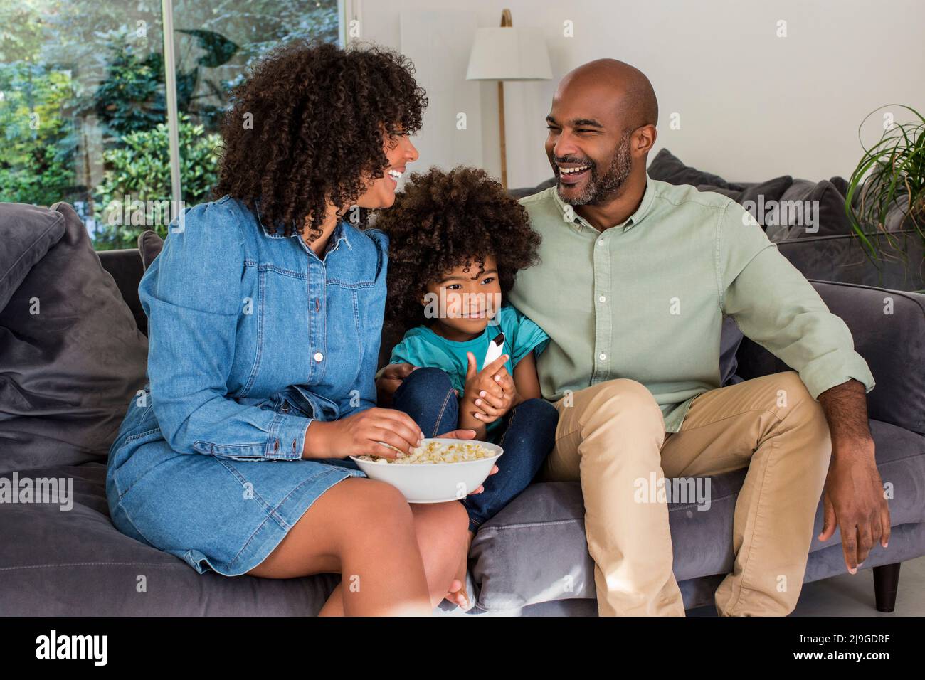 Happy family watching television together while sitting on sofa Stock Photo