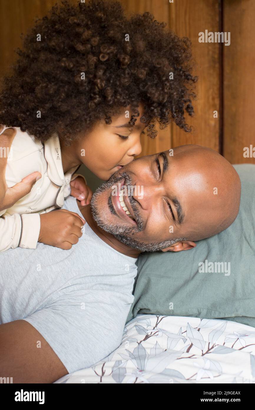 Daughter kissing her father on bed Stock Photo