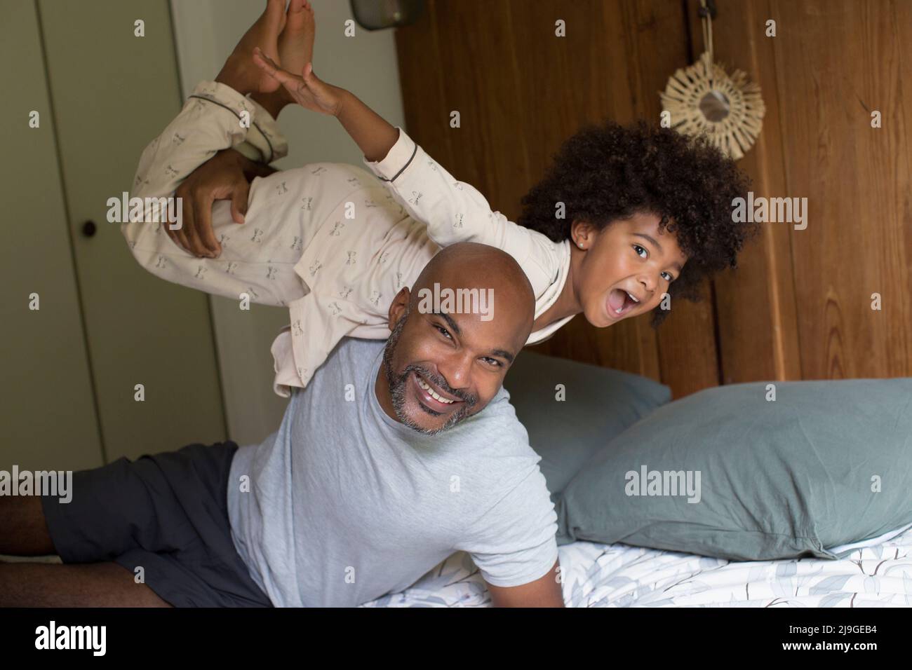 Smiling father carrying his daughter on shoulder in bedroom Stock Photo