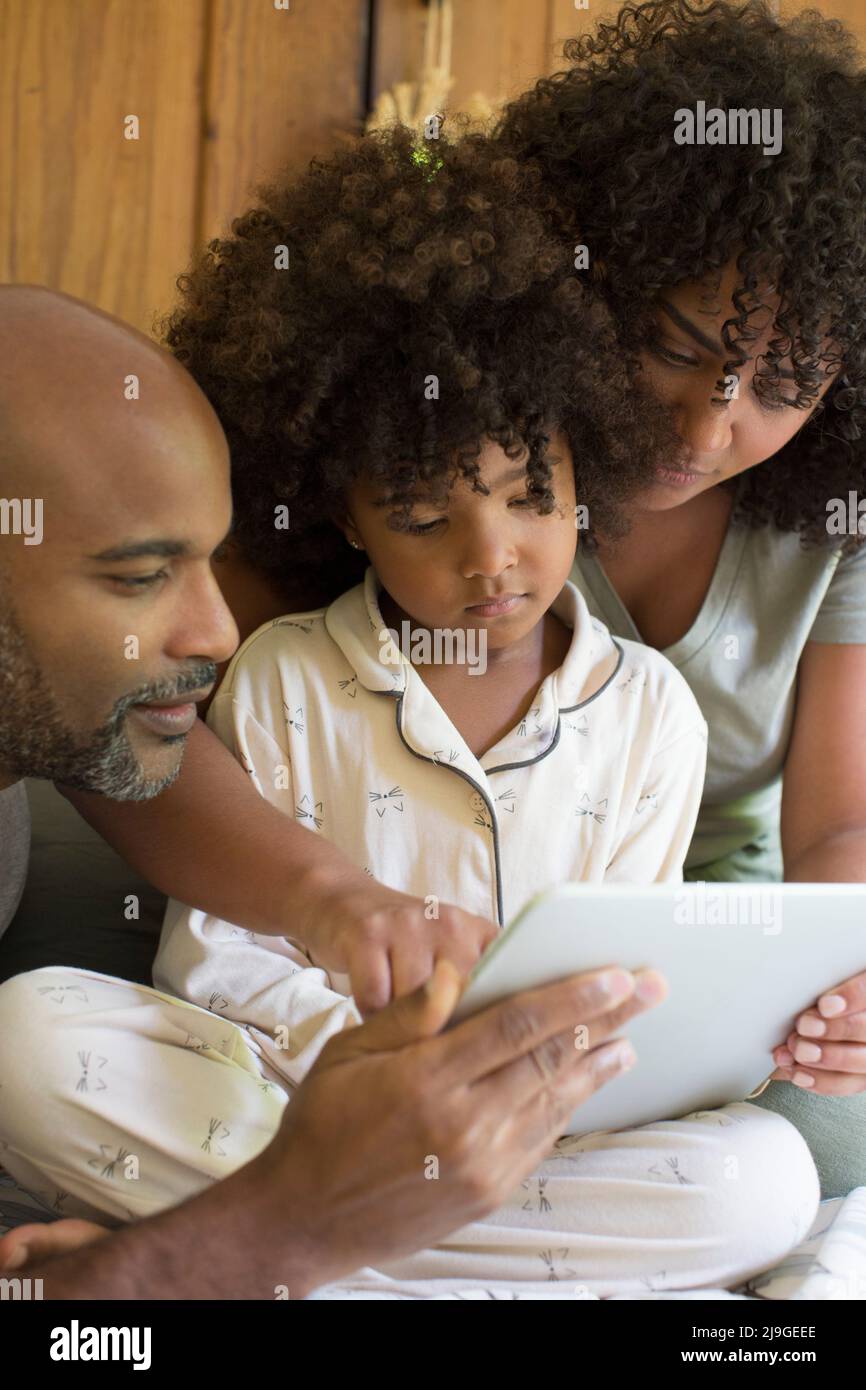 Parents with daughter using digital tablet in bedroom Stock Photo