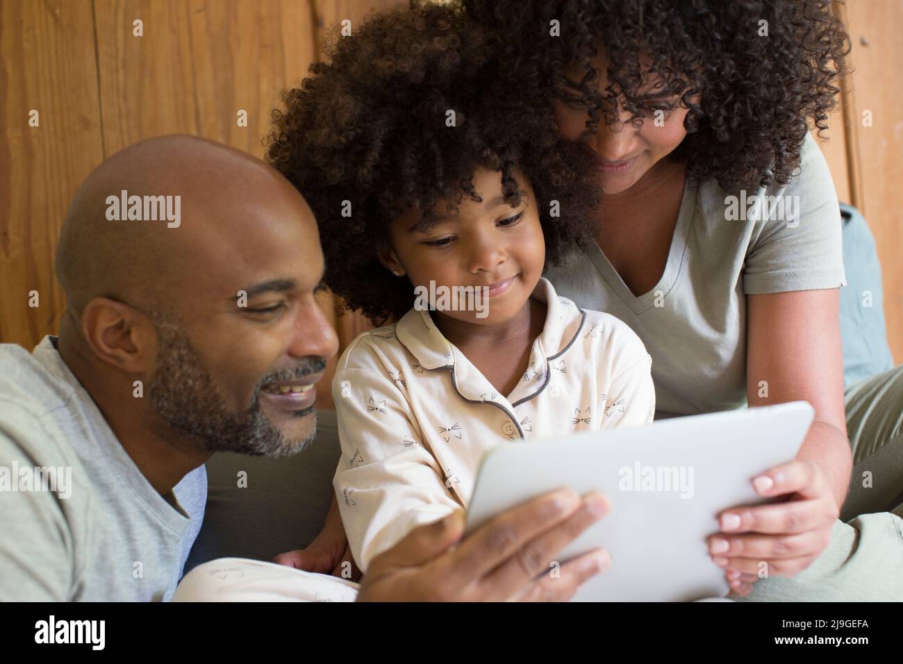 Parents with daughter using digital tablet in bedroom Stock Photo