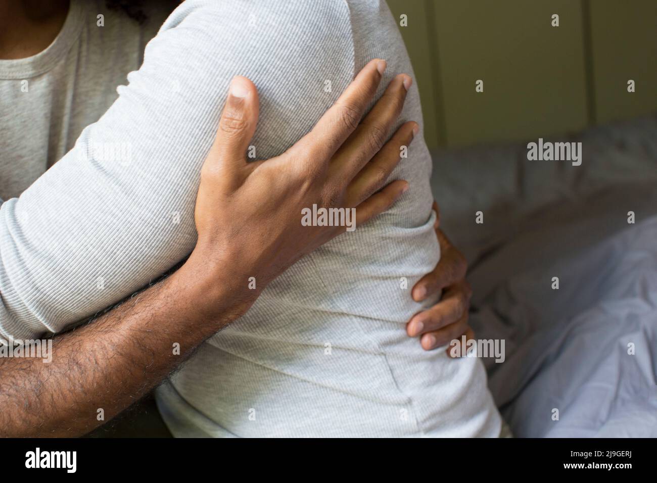 Hand of a man holding a woman sitting on bed Stock Photo