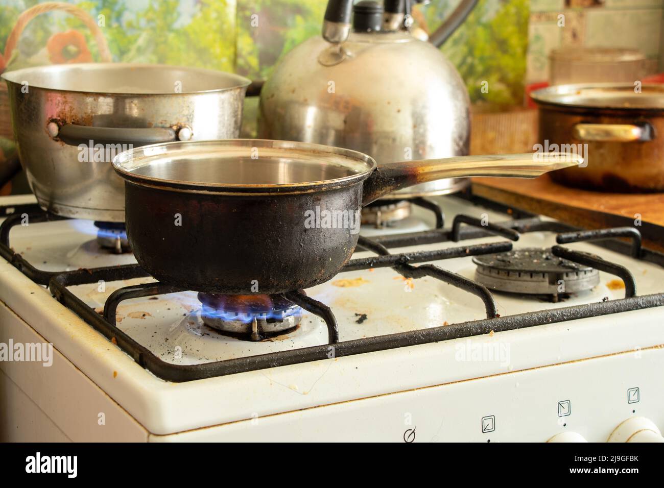 a dirty saucepan stands on a dirty gas stove in the kitchen at home