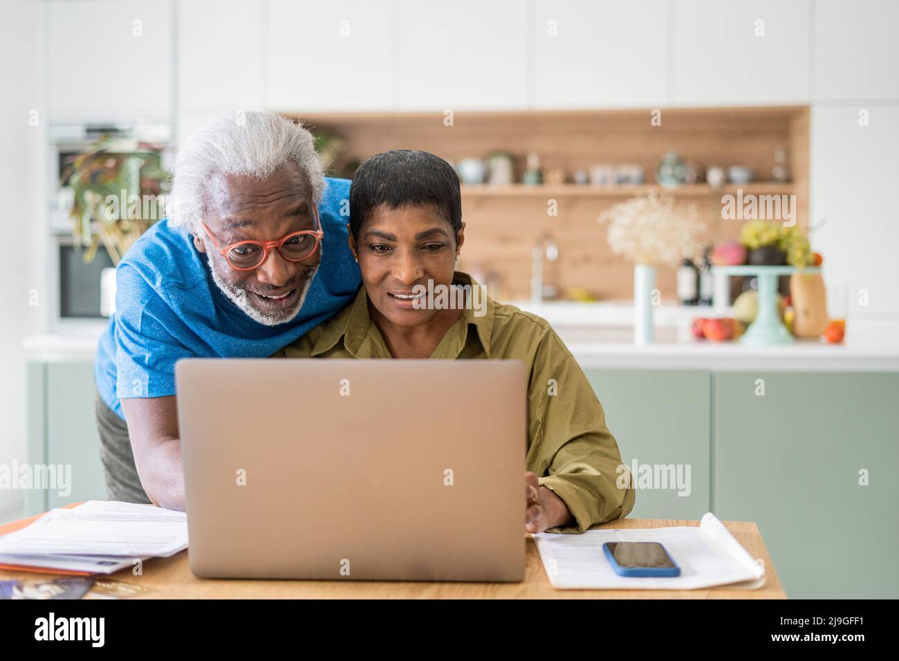 Couple using laptop in kitchen Stock Photo