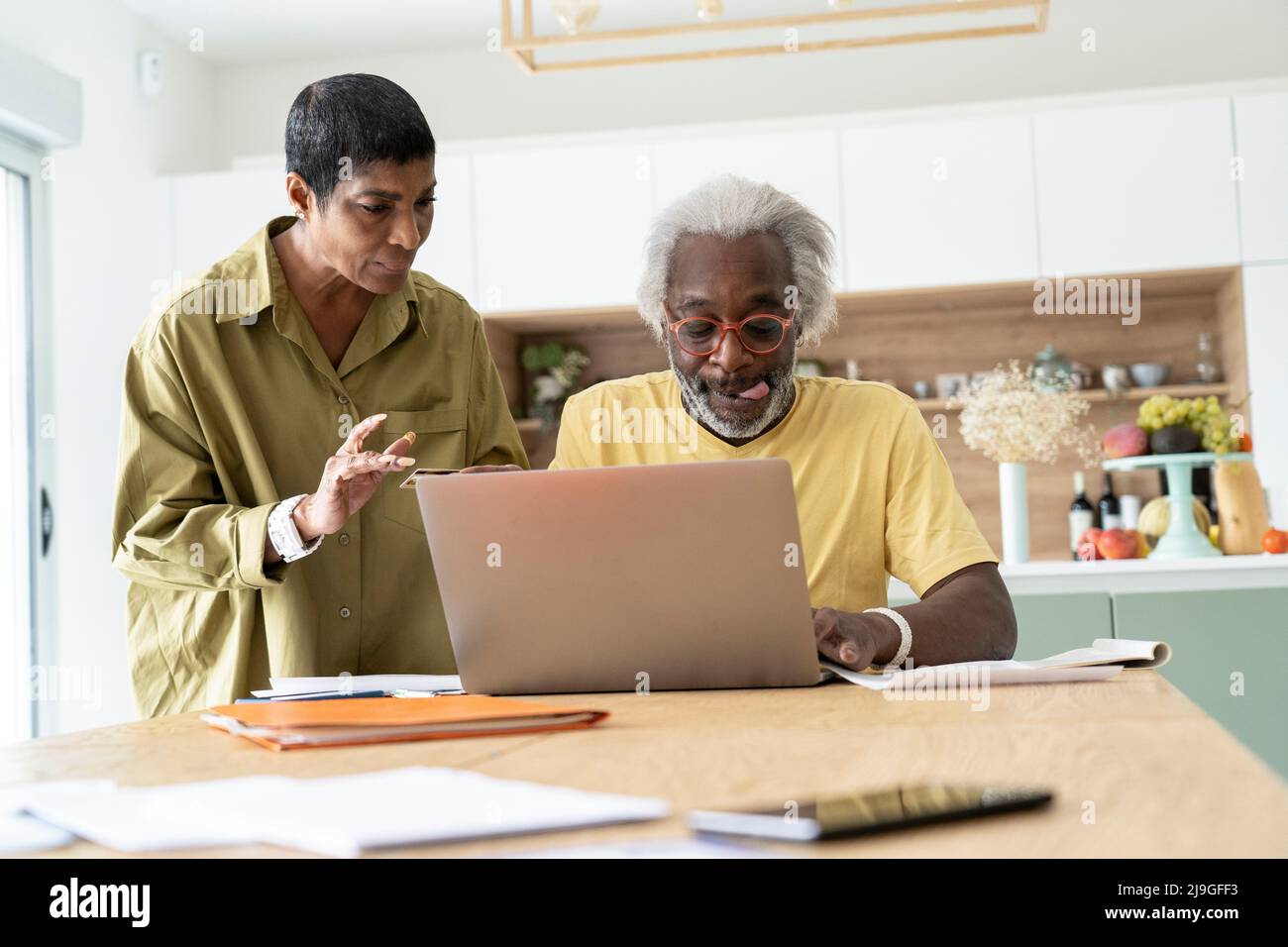 Couple using laptop in kitchen Stock Photo