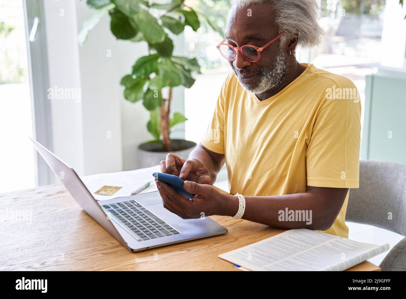 Senior man using smart phone and laptop Stock Photo