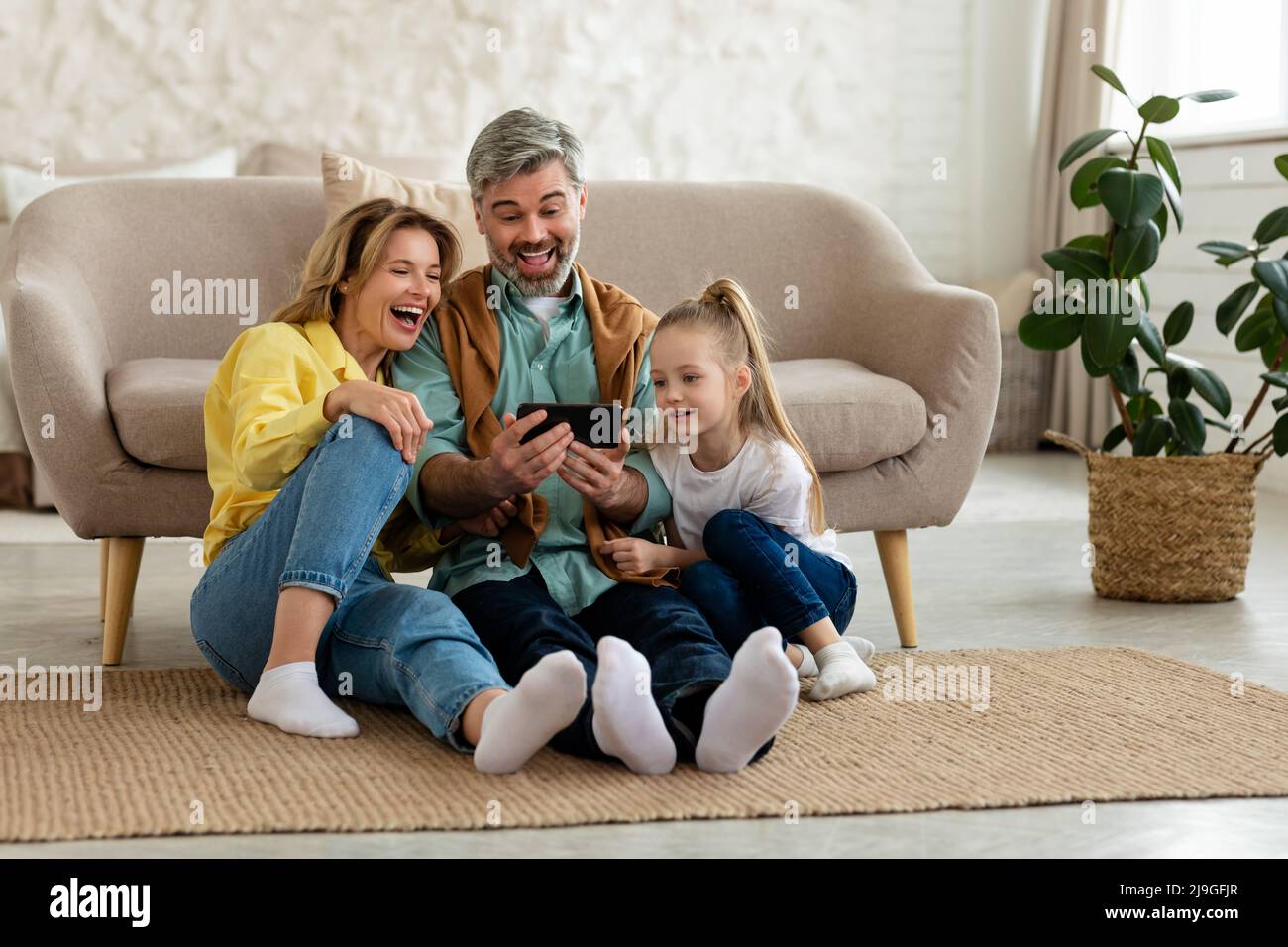 Joyful Family Using Mobile Phone Laughing Browsing Internet At Home ...