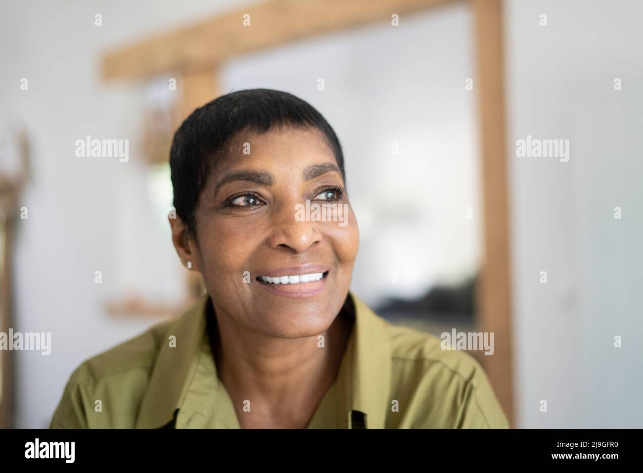 Smiling mature woman sitting in living room Stock Photo