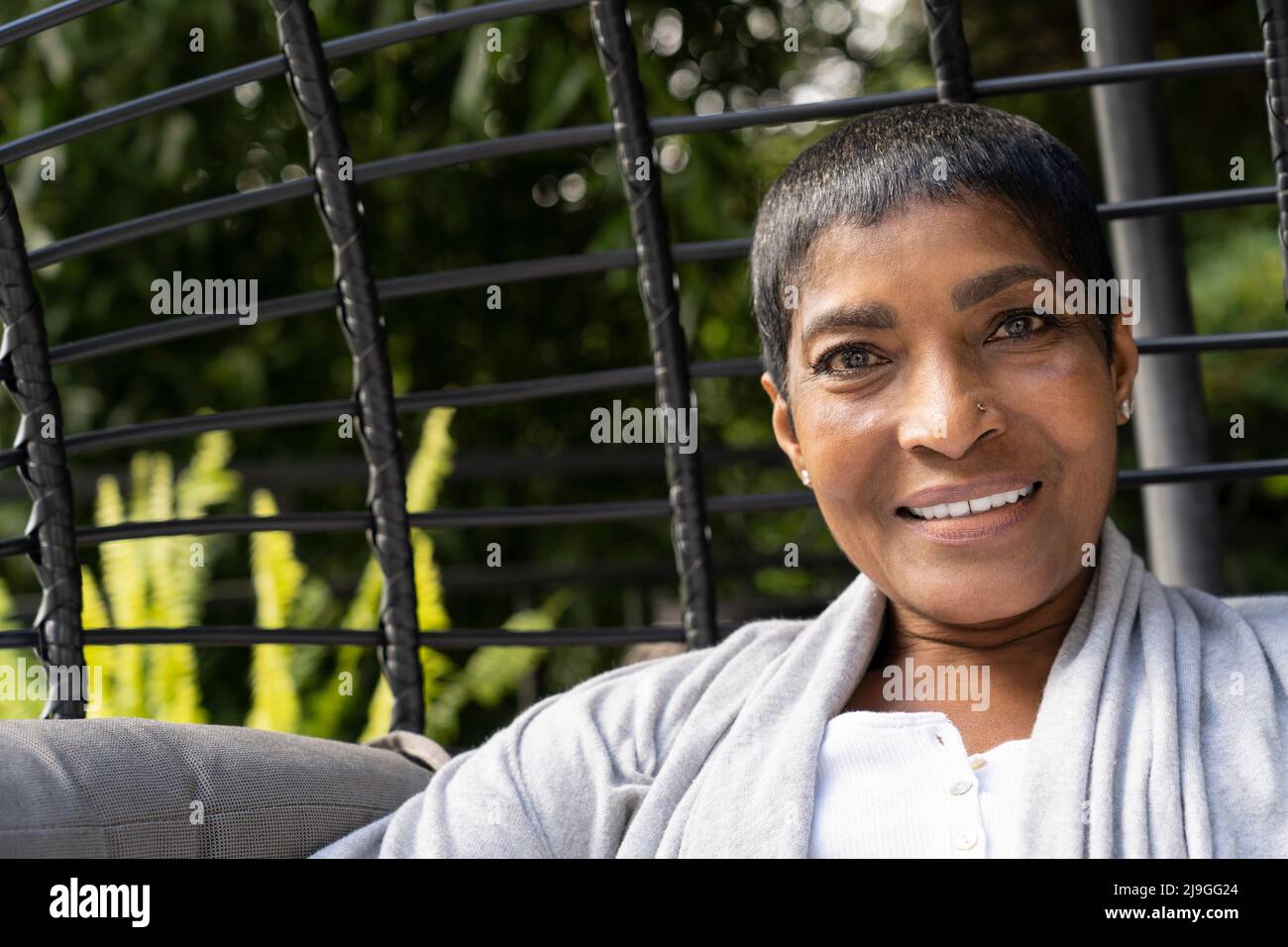 Smiling mature woman sitting on swing chair Stock Photo