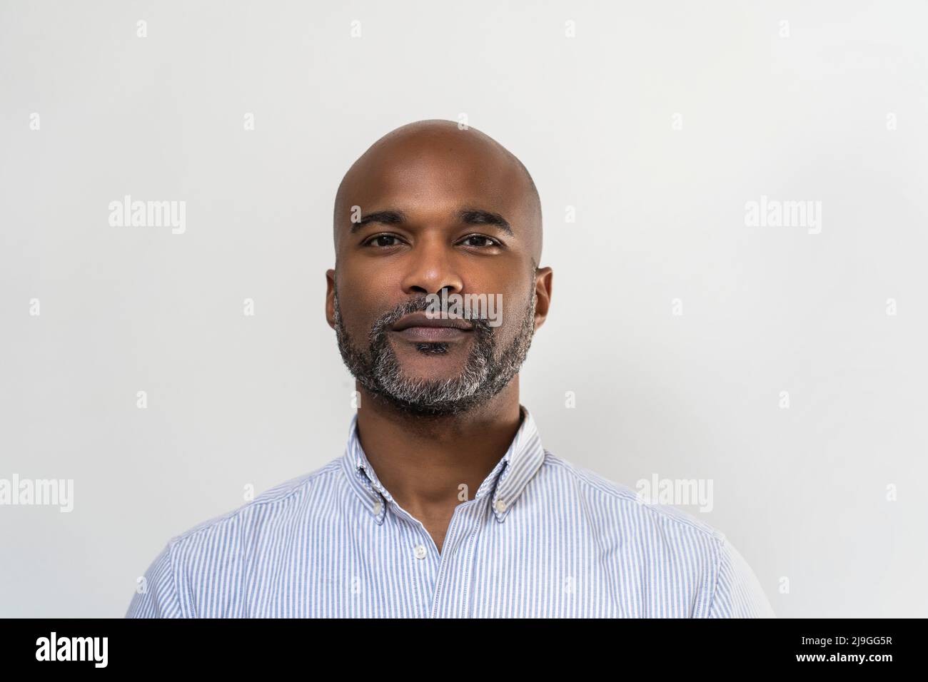 Close-up of smiling man standing against white wall Stock Photo