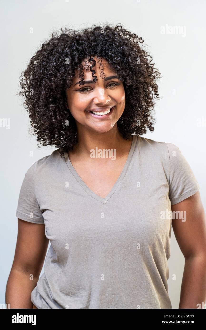 Smiling woman standing against white wall Stock Photo