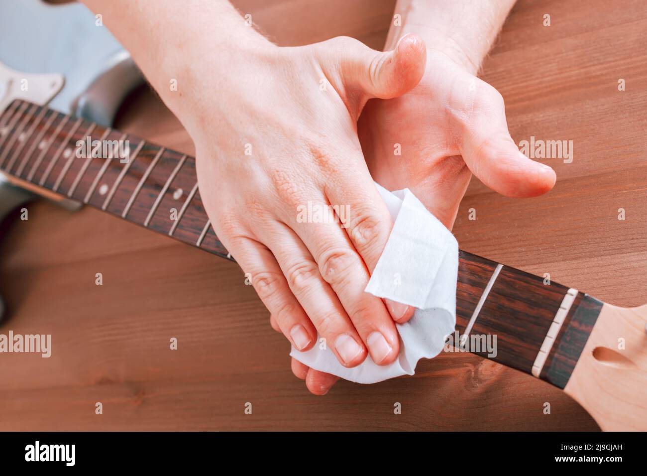 Guitar master polishing fretboard of electric guitar, close up shot of