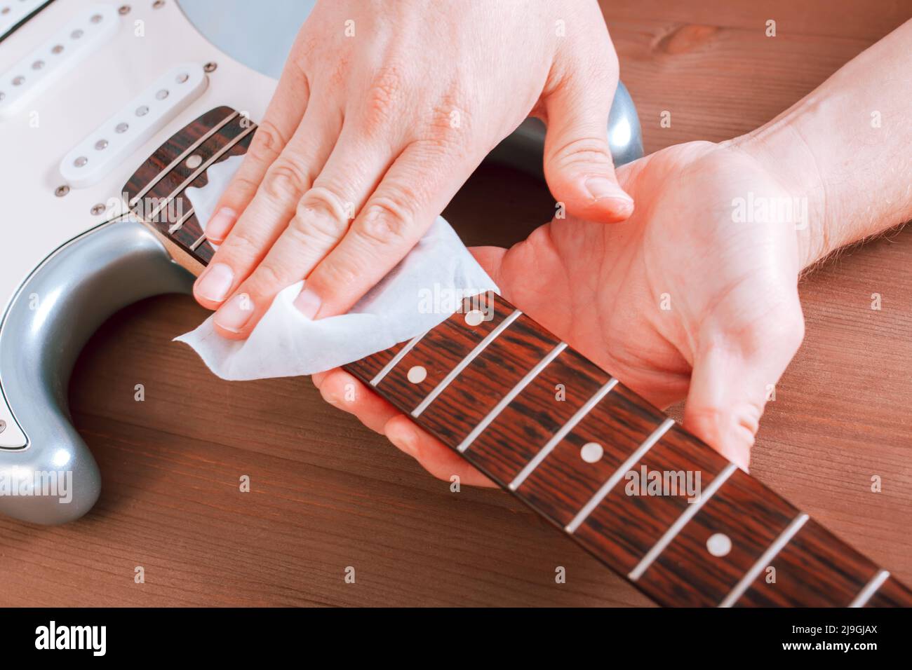 Guitar master polishing fretboard of electric guitar, close up shot of