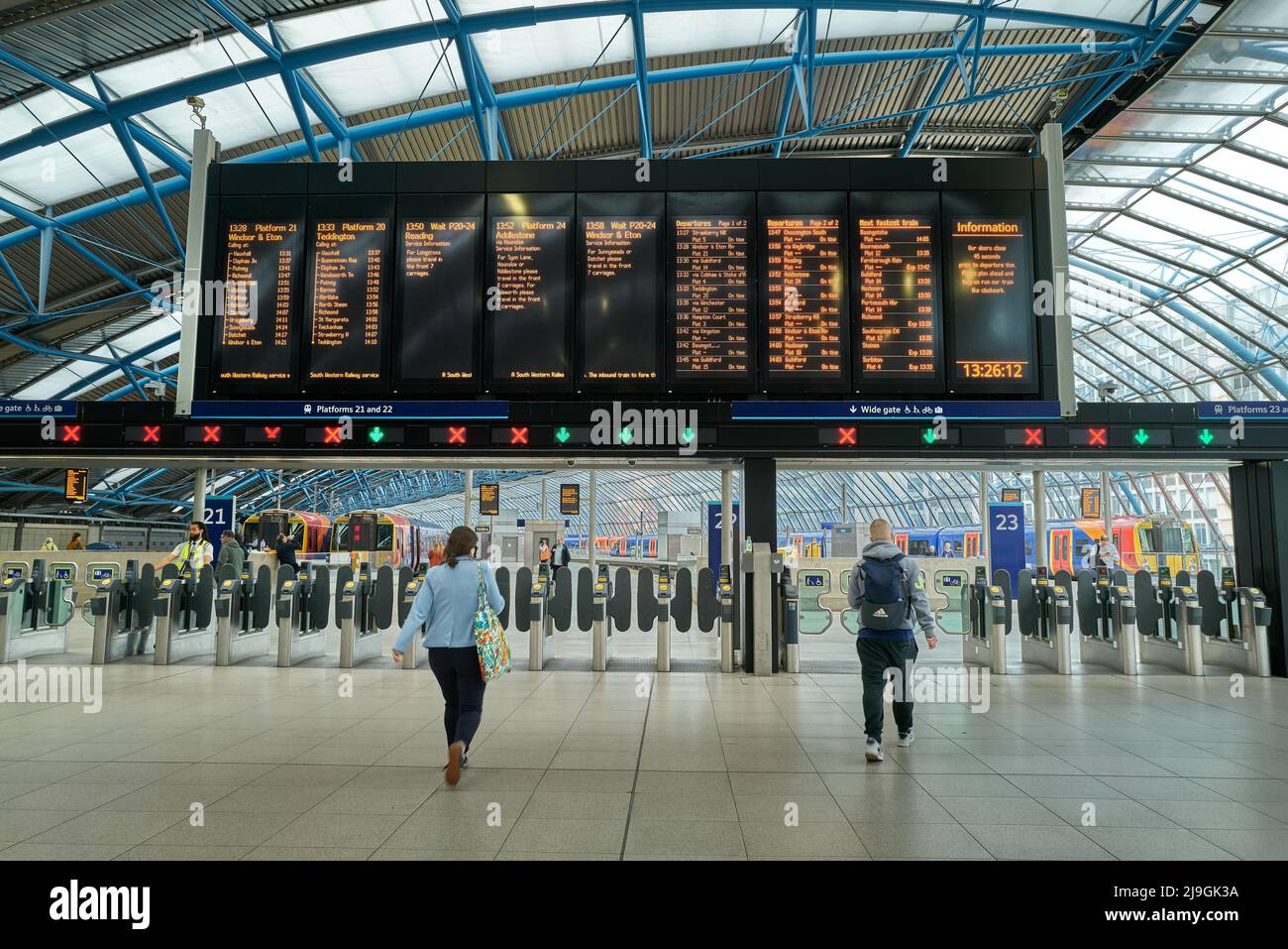 Passengers look at the train timetable board at Waterloo railway