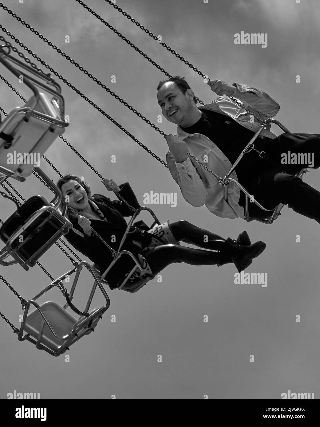 2 people enjoying life flying by overhead on an amusement ride Stock Photo