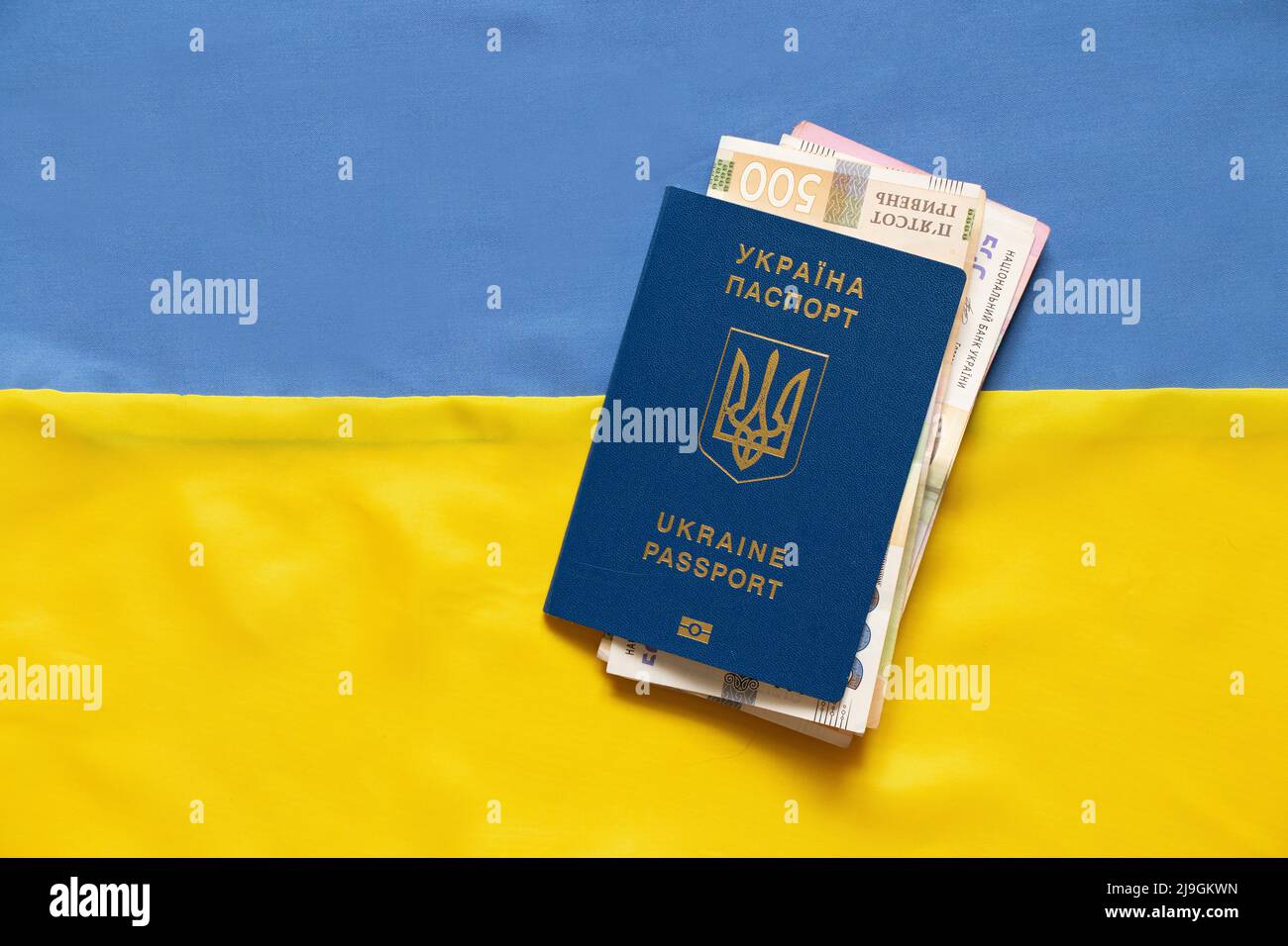 Biometric foreign passport with money lies on the national flag of Ukraine yellow-blue Stock Photo