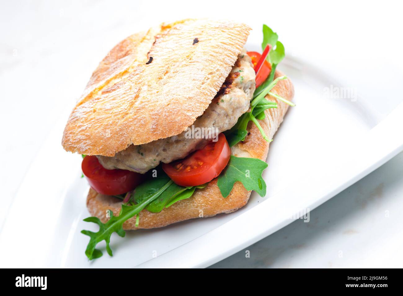 homemade turkey burger with cherry tomatoes and arugula in ciabatta