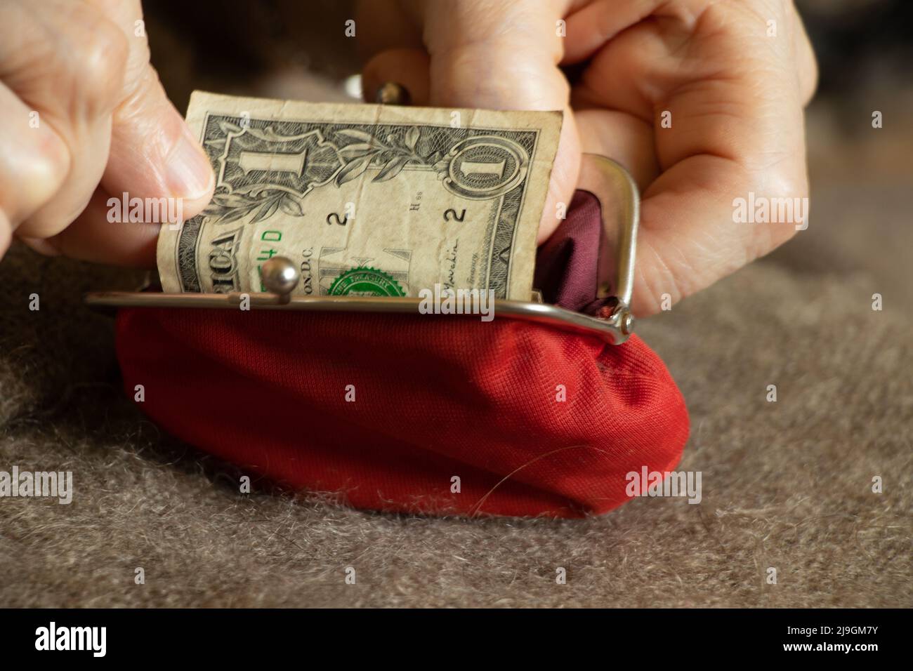 old woman's hands take out a dollar bill from a soft red wallet, money in a wallet, finance Stock Photo