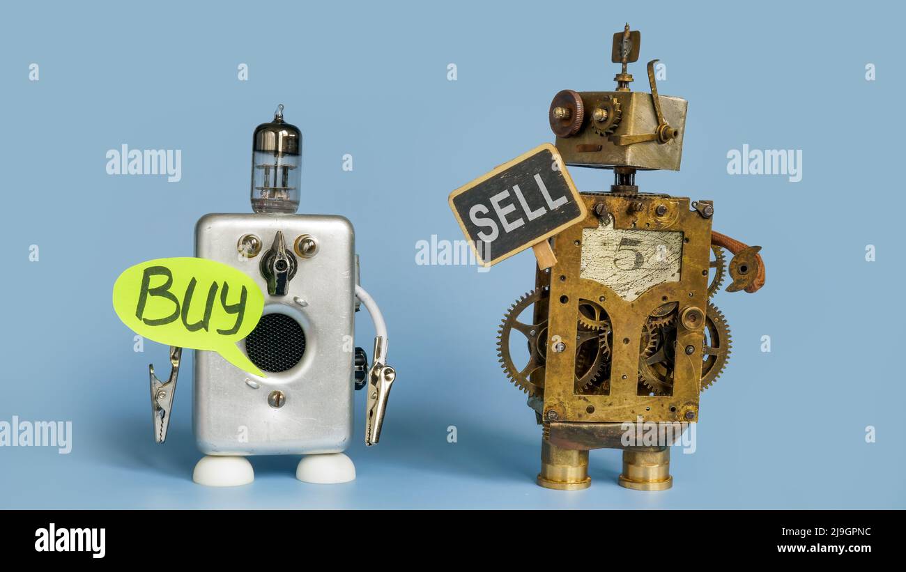 One robot is holding a sell sign, the other is buy. Stock Photo