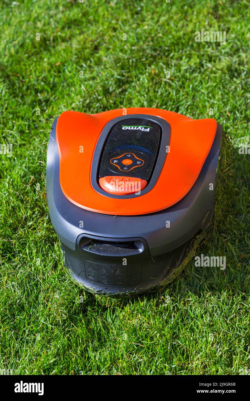robotic Flymo lawnmower cutting grass lawn in May - compact robotic lawnmower with simple Push & Go interface and advance smartphone control Stock Photo