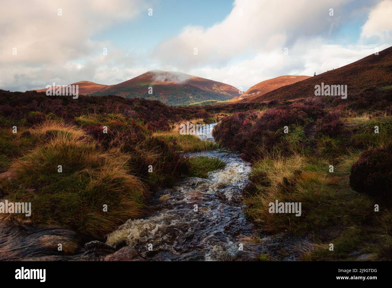 A river runs through a Scottish landscape in the majestic and wild Highlands of Cairngorms National Park. Stock Photo