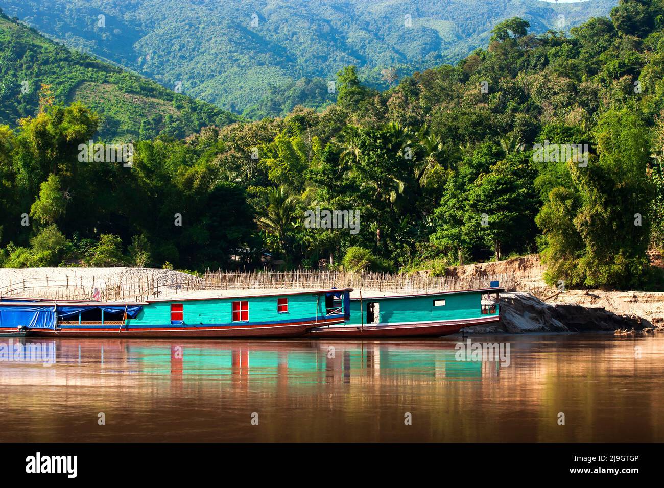 Traditional Laos ferry boats dock on the Mekong Riverbank. Luang Prabang, Laos. Stock Photo