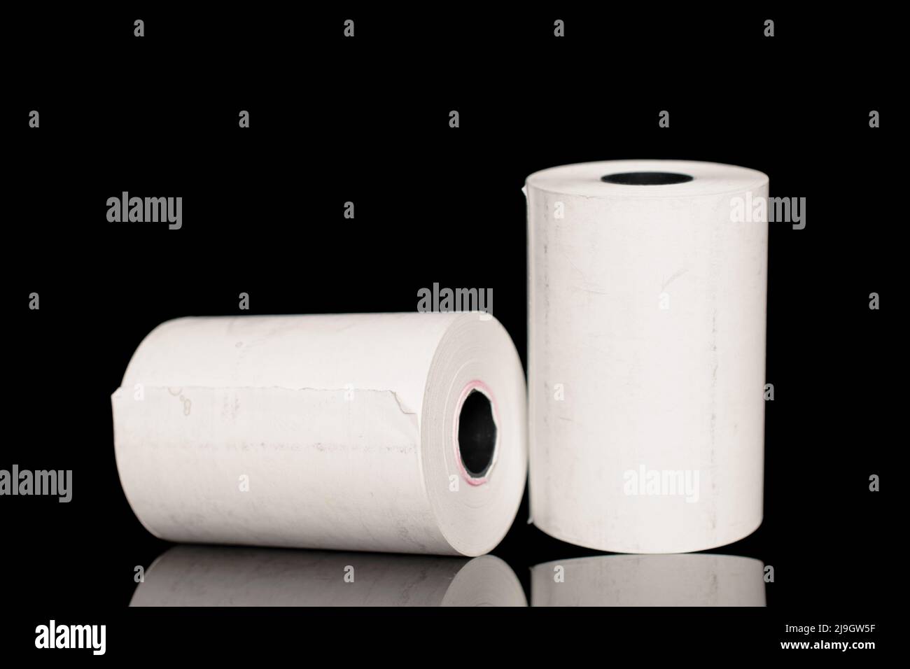 Two rolls of paper cash register tape, closeup isolated on black Stock