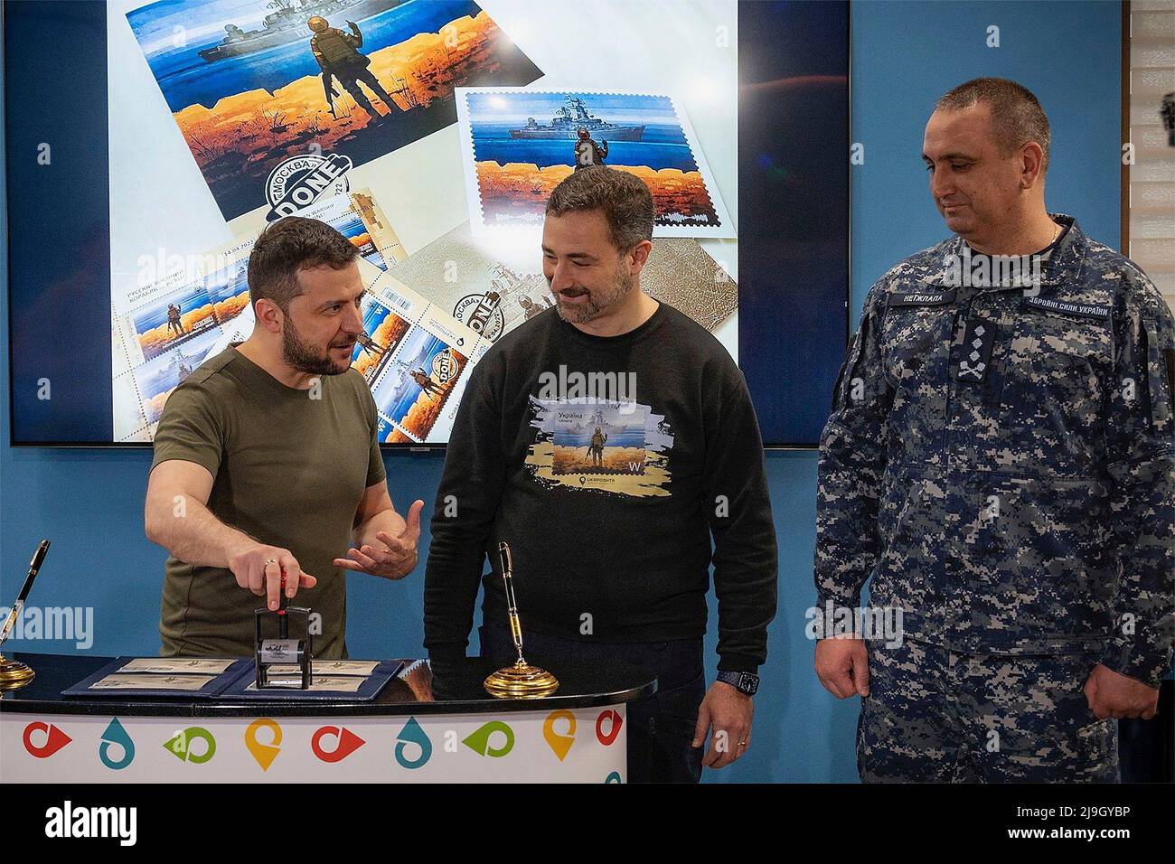 Kyiv, Ukraine. 23rd May, 2022. Ukrainian President Volodymyr Zelenskyy, left, uses the cancelation stamp on a collector set of the Russian Warship series postage stamp minted by the Ukrposhta, May 23, 2022 in Kyiv, Ukraine. Ukrposhta CEO Smilyanskyi Ihor, center, and Vice Admiral Oleksiy Neizhpapa, right, look on. Credit: Ukraine Presidency/Ukrainian Presidential Press Office/Alamy Live News Stock Photo